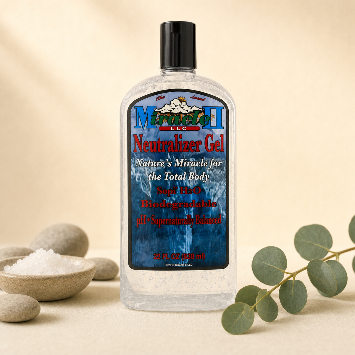 Miracle II Neutralizer Gel 22 fl oz bottle on a warm cream background with river stones, mineral salt and eucalyptus