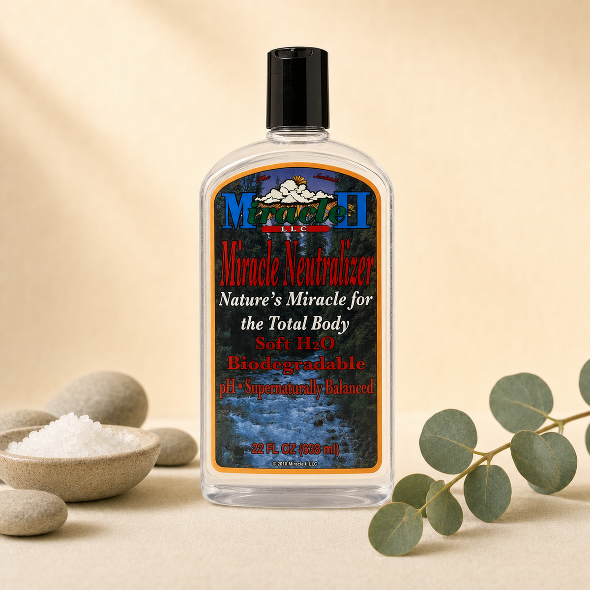 Miracle II Miracle Neutralizer 22 fl oz clear liquid bottle on a warm cream background with river stones, mineral salt and eucalyptus
